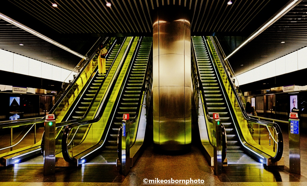 Yellow-lit escalators at Canary Wharf Elizabeth Line station